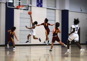 Ian James, freshman, jumps up to shoot the basketball in the hoop whilst members of Lake Hamilton race to stop him. Braylen Clegg supports from behind for backup. This happened on November 27.