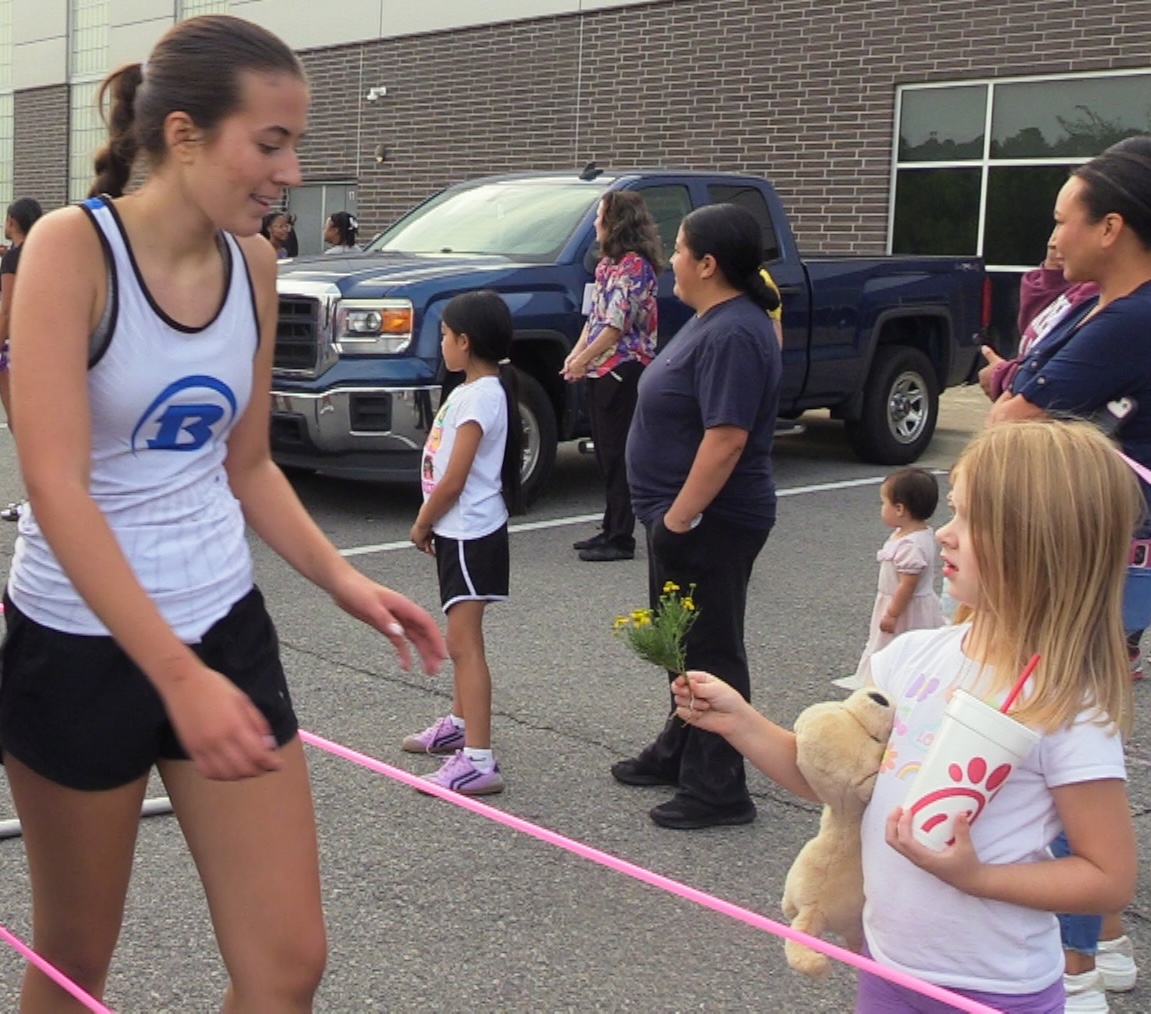 Regina Perez is handed flowers by a girl at the finish line of the Intra Squad cross country meet.